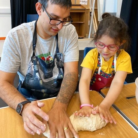 Father and daughter kneading dough at a cookery workshop