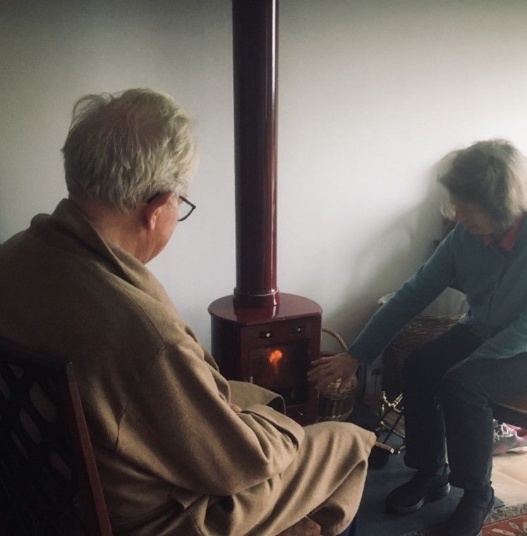 Two pensioners sitting by a fire, trying to warm up