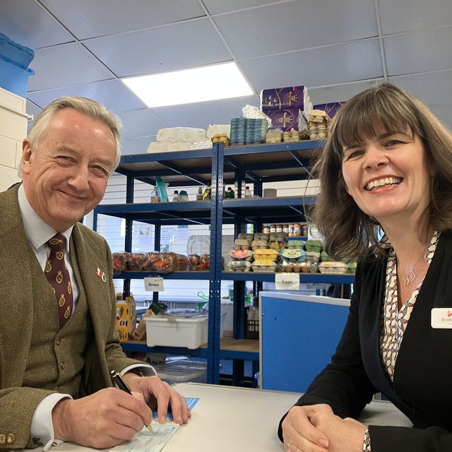 Robert Robinson at Ledbury Food Bank writing a cheque for the Surviving Winter appeal, accompanied by Bridie Sullivan from Herefordshire Community Foundation